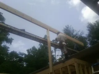 Carpenter setting a ridge beam over a new addition frame — Ice Dam Removal by Roofing Brothers in Byron Center