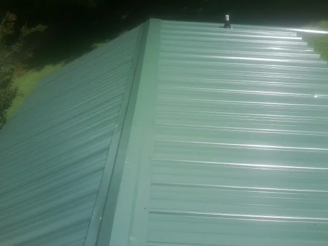 New green metal panels meeting at the ridge of a roof in Byron Center