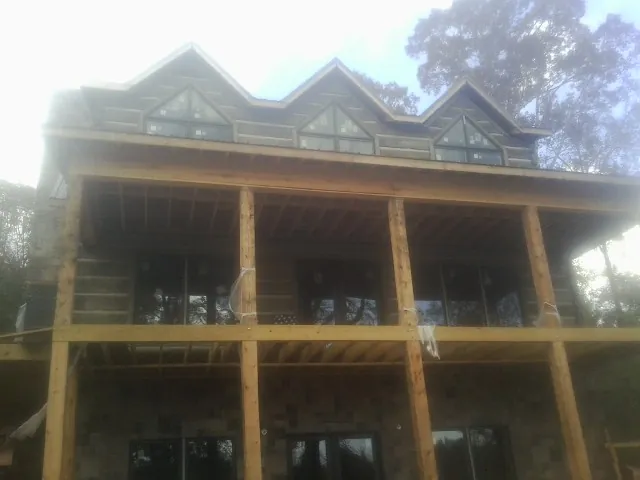 Dormers and porch framing on a large log home under construction — Roof Coating work by our crew in Byron Center