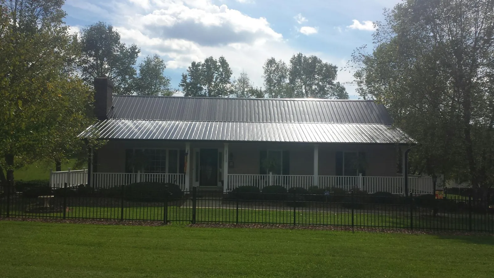 Gray metal roof on a brick ranch with a full width front porch — Gutter Guard Installation work by our crew in Byron Center