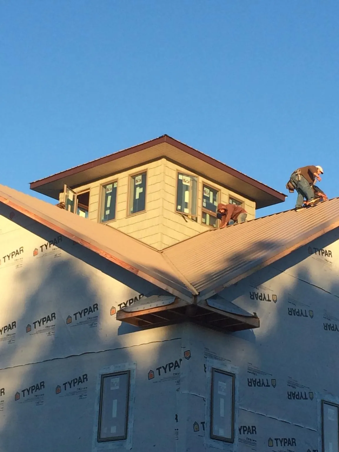 Roofers working around a rooftop cupola on a new metal roof at sunset — Roof Waterproofing in Byron Center by Roofing Brothers